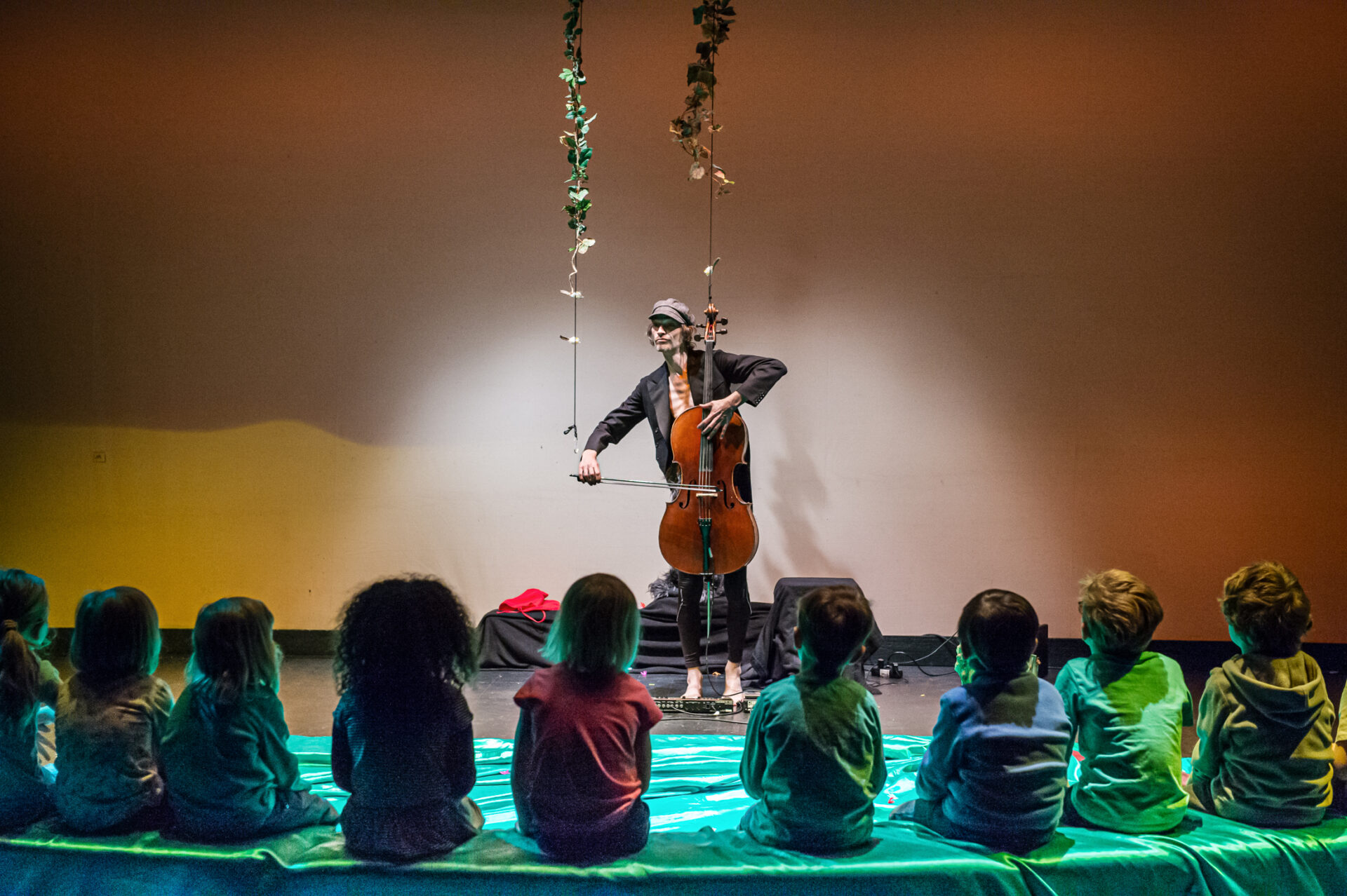 Mit dem Cello vor sitzenden Kindern
